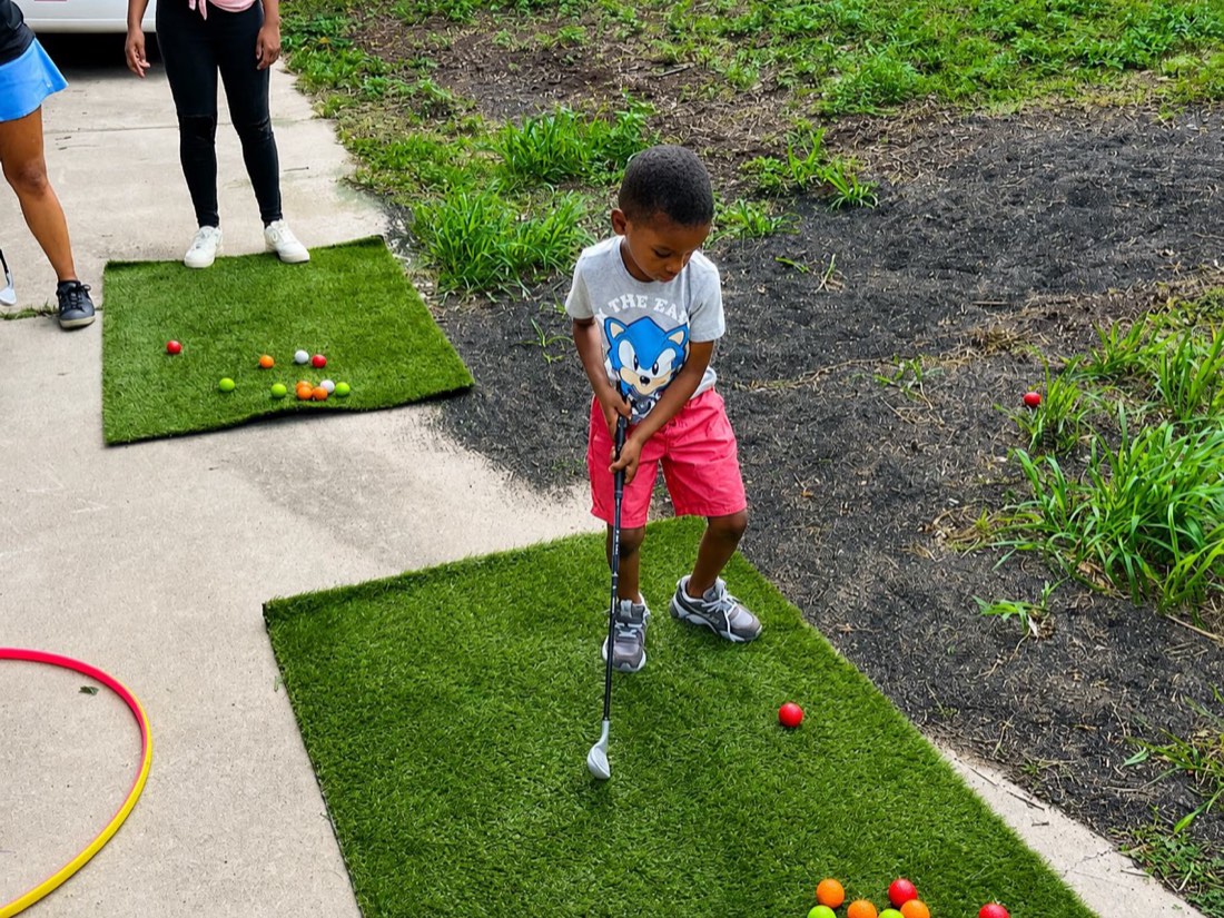 A camper practicing mini golf on an outdoor putting green