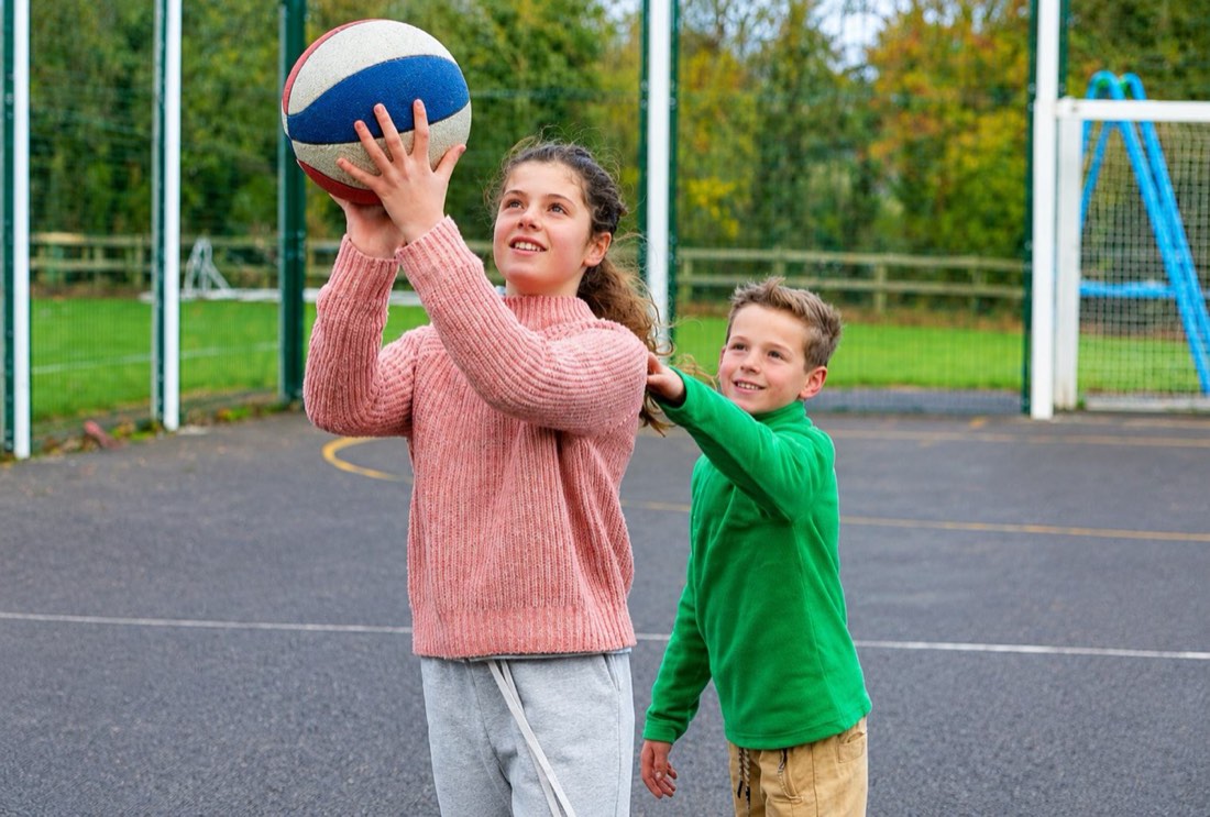 A camper taking part in an outdoor activity with a friend assisting